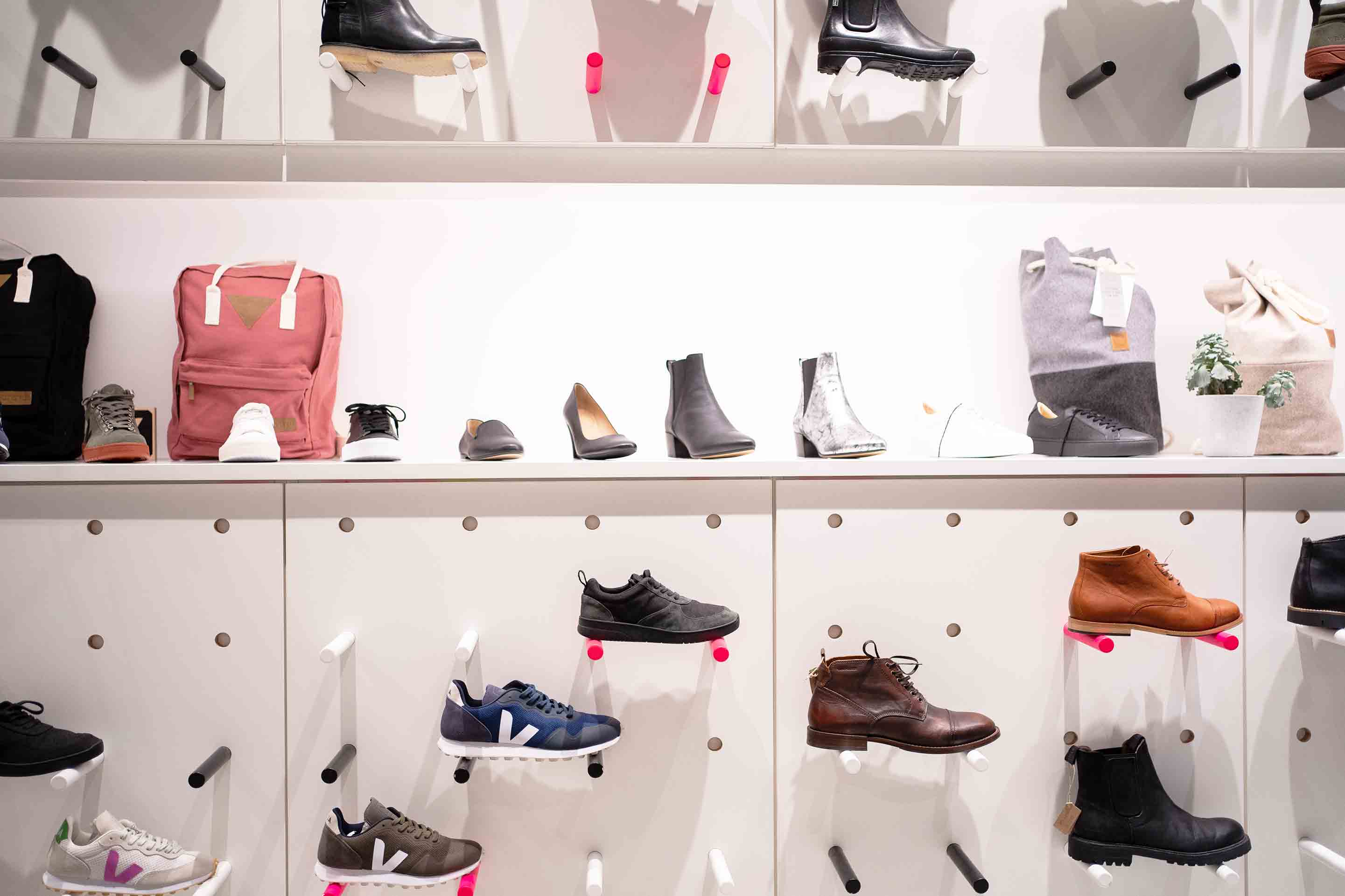 Steckregal in weiß, schwarz und pink zur Präsentation der verschiedenen, nachhaltigen Schuhmodelle, wie Sneaker, Winterstiefel und auch Rucksäcke und Seesäcke