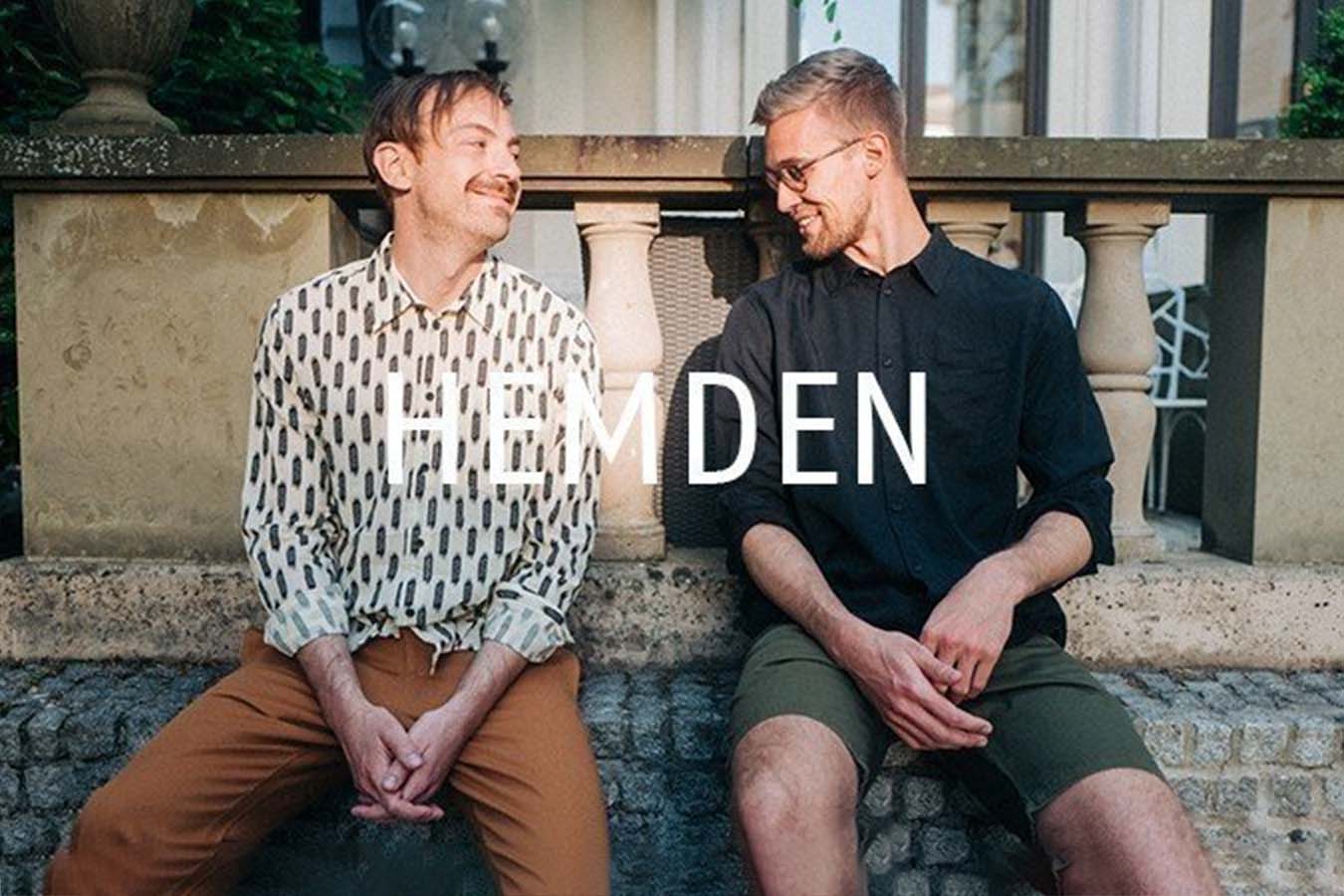 Zwei Männer sitzen vor einem Haus in der Sonne und tragen Hemden mit Muster und unifarben aus nachhaltiger und fairer Produktion