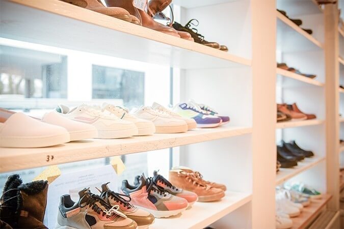 Regale im Schaufenster mit aufgereihten, nachhaltigen Schuhen, wie Sneaker und Stiefel in verschiedensten Farben und Größen für alle Geschlechter.