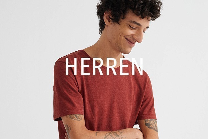 Vegane Kleidung Herren, lachendes Model mit rotem T-Shirt aus Hanf und tätowierten Armen